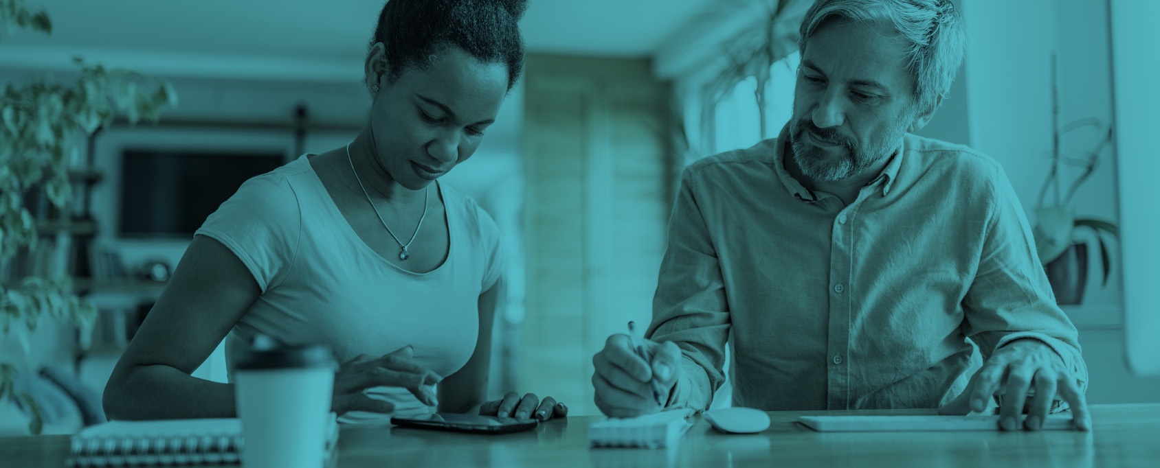 two people look at cell phone and laptop