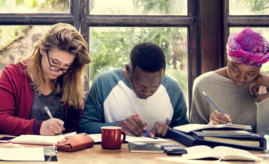 Three students studying shoulder to shoulder in the library