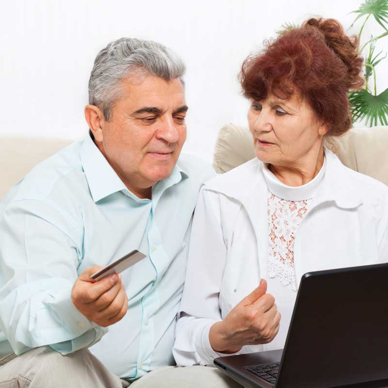 Senior couple using laptop holding a credit card