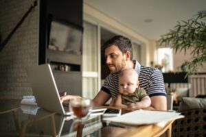 man with a baby in his lap looking at a computer screen