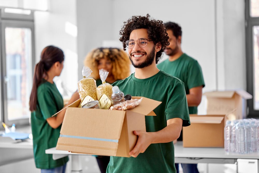 A man holds a box of food and smiles.
