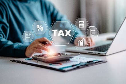 A person at a laptop and words of tax in front of him